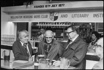 Johnny McGuigan, Bud Millar and Owen Banks enjoy a beer on the centenary of the Wellington Working Men's Club and Literary Institute, 9th of July 1977     View of patrons and bar facilities, Wellington Working Men's Club.. Further negatives of the Evening Post newspaper. Ref: EP/1977/2627/5A-F. Alexander Turnbull Library, Wellington, New Zealand. http://natlib.govt.nz/records/23183845