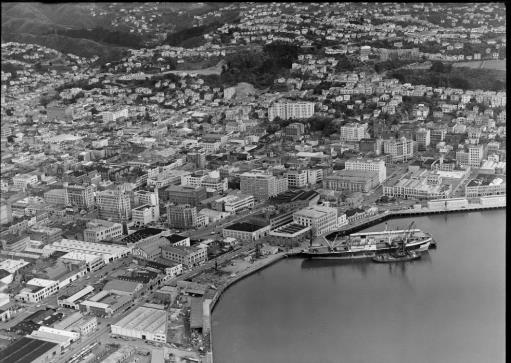 1956 – aerial photograph of Wellington. The Taranaki Street gates can be seen next to Shed 22 (1919 – 21). National Library reference: Wellington Harbour southern wharf area with Cable and Taranaki Streets and city, with Kelburn Park and Victoria University, Wellington City. Whites Aviation Ltd :Photographs. Ref: WA-40792-G. Alexander Turnbull Library, Wellington, New Zealand. /records/30113905 