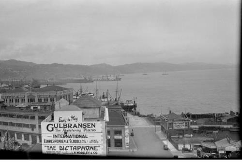 c.1929 view of the Taranaki Street wharf gates. National Library reference: Wellington city scene including the intersection of Taranaki and Cable Streets. Just, F R :Two albums of photographs and captions relating to the Just family and 119 negatives taken by his father in the 1920s and 1930s of around Wellington and the Bell Bus Company. Ref: 1/2-071478-F. Alexander Turnbull Library, Wellington, New Zealand. /records/23117809