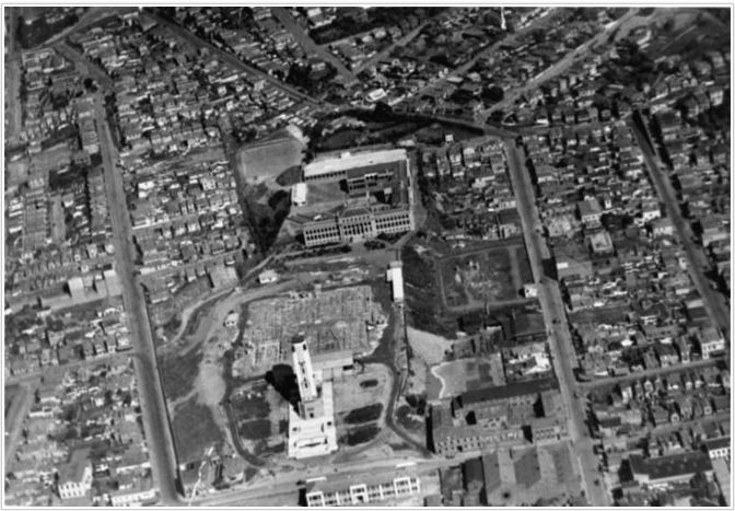 1933 – Aerial view over Mt Cook, while the Dominion Museum was under construction. The Mt Cook Police Station is at the bottom-left of the image, the Carillon at the bottom-centre, army buildings can be seen at the bottom-right, and the Wellington High School at the centre-top. National Library reference: Aerial view over Mount Cook, Wellington, while the Dominion Museum was being constructed. Ref: 1/2-053018-F. Alexander Turnbull Library, Wellington, New Zealand. /records/23021711 